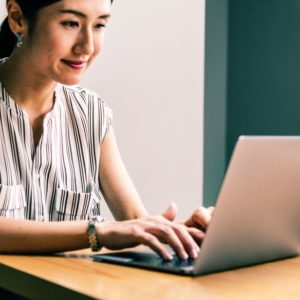 Smiling resume writing career woman typing on her laptop