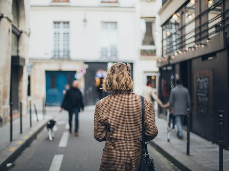 A short haired woman in square patterned coat walking in the streets to look for a successful career change