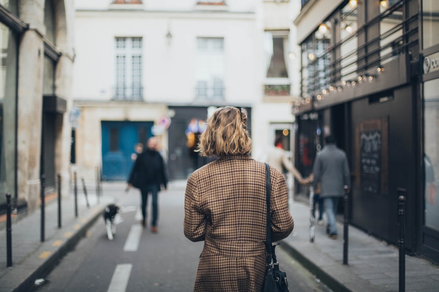 A short haired woman in square patterned coat walking in the streets to look for a successful career change