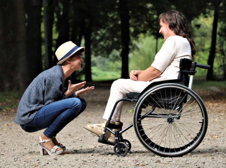 Happy woman sitting in front of a woman in a wheelchair telling about careers for people with disabilities