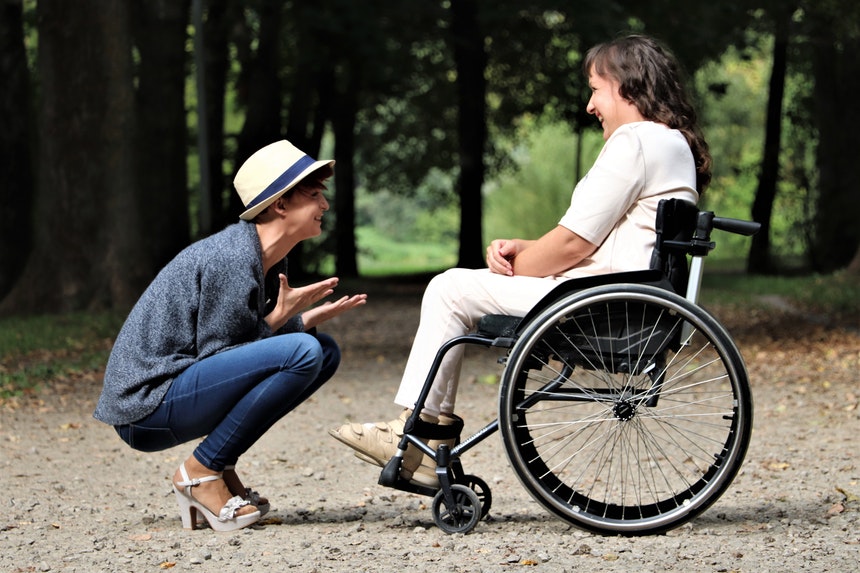 Happy woman sitting in front of a woman in a wheelchair telling about careers for people with disabilities