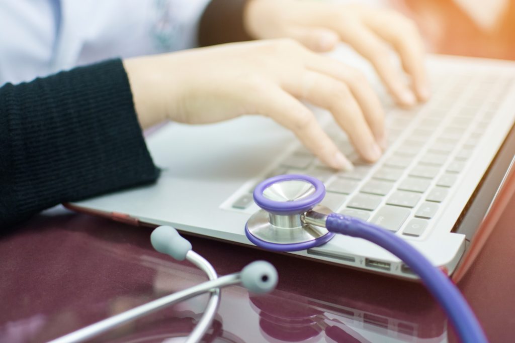 healthcare worker typing on laptop keyboard