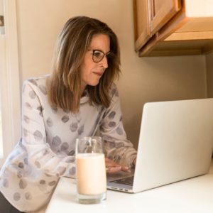 A working mom using her laptop with a glass of milk at her side