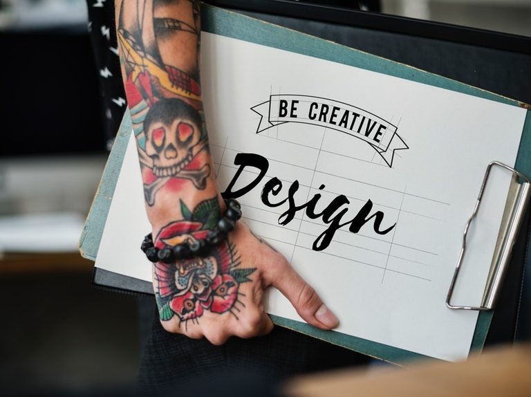 tattooed arms carrying creative resumes and portfolio
