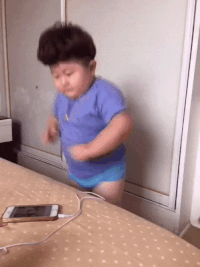 A happy baby dancing in front of his charging phone