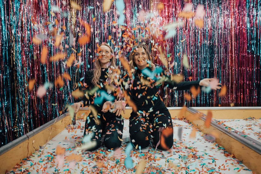 Two woman enjoying the party game ideas with a lot of colorful confetti