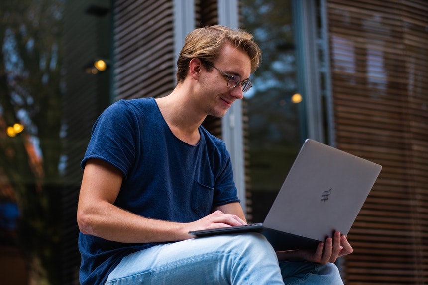 a happy man holding a laptop while writing the best resume