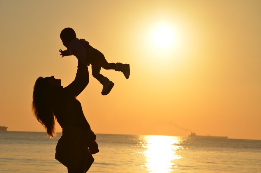 A working mother carrying her child along the shores of a beach