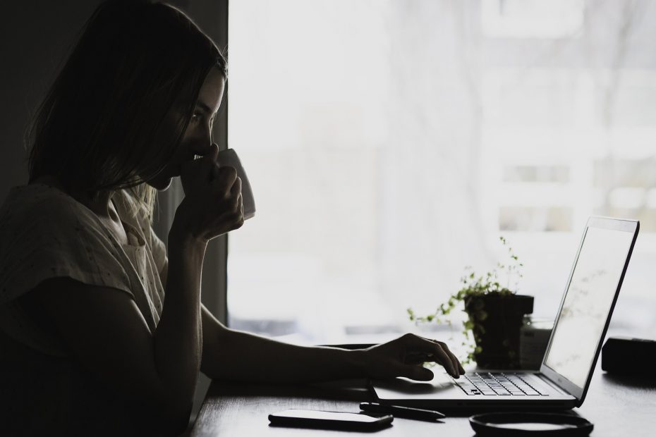 Lady drinking coffee while browsing on laptop