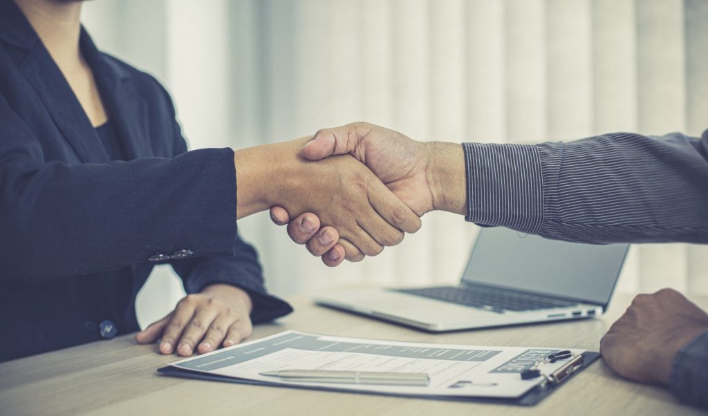 hiring manager and job applicant shake hands as the latter accepts the job offer