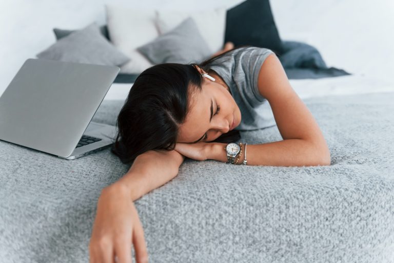 Lazy day for woman in casual clothes that lying down at home on the bednear laptop
