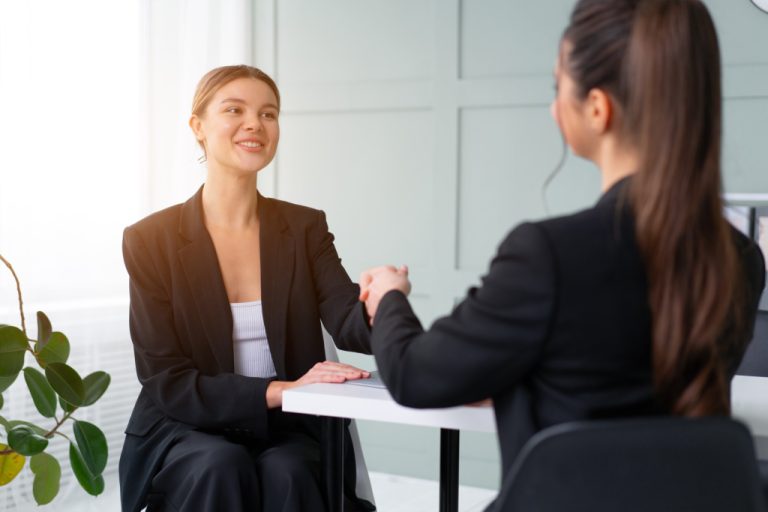 A woman showing great job interview body language is shaking hands to the employer