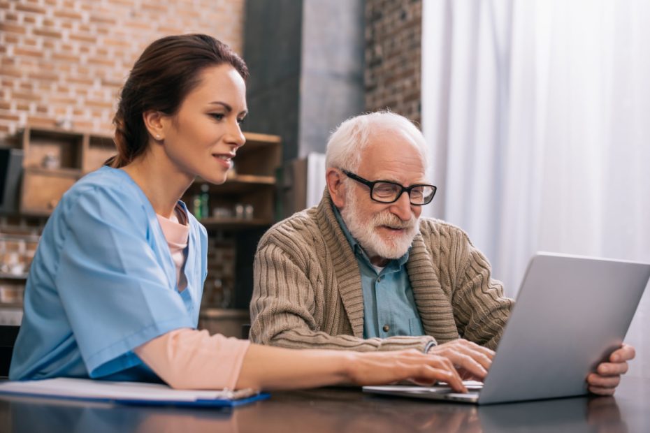 Medical assistant assisting patient in laptop.
