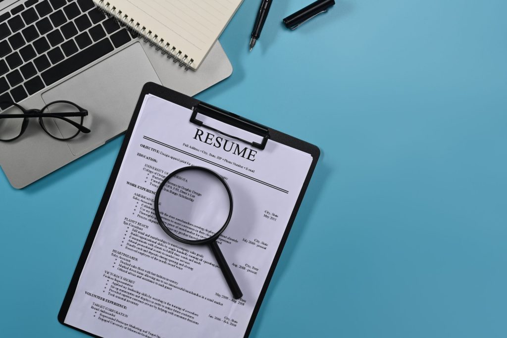 A resume with magnifying glass focusing on resume sections.